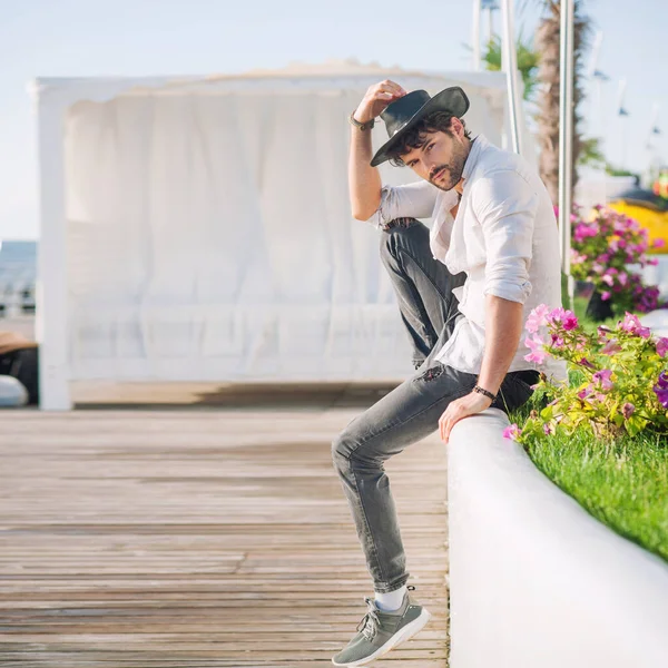 黒の帽子と白のシャツに身を包んだ男モデル 観光熱帯都市の風景に対する屋外写真 — ストック写真