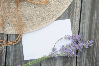 Ahşap zemin üzerinde lavanta çiçekleri ve güneş şapkası olan boş uzay beyaz listesi, üst görünüm, yatay