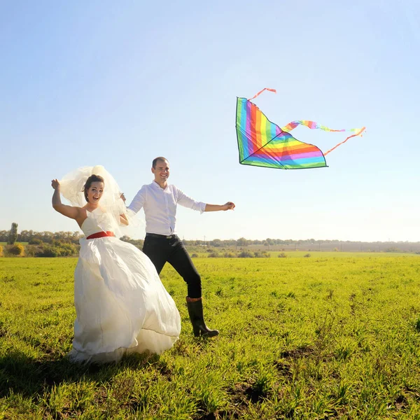 快乐的年轻夫妇带着放飞的风筝在田里散步 — 图库照片