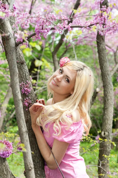 可愛いです若いです女性の肖像画ともにブロンド髪ポージングでピンクの花春の庭 — ストック写真