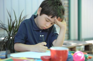 Küçük çocuk evinin arka bahçesinde ödevini yapıyor.