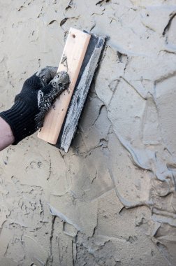 Dekoratif alçı kaplama, usta Venedik sıvalarının dokusunu duvarda malayla yapıyor, yüzü yok, sadece eli var.