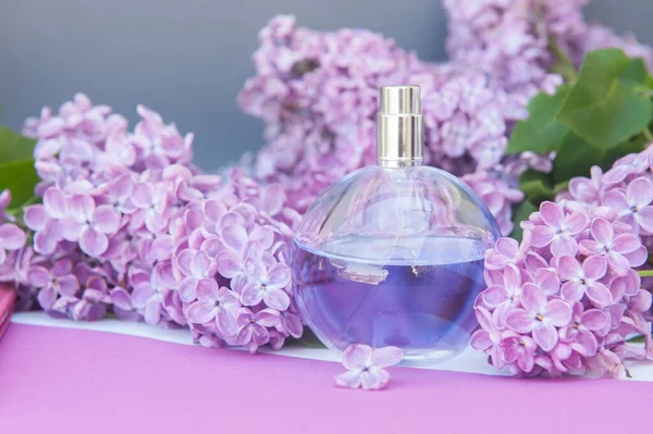 Fioletowe Kółko Butelka Perfum Tle Liliowymi Kwiatami — Zdjęcie stockowe