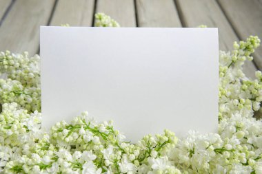 Kapalı beyaz leylak çiçekli beyaz kağıt kart ve ahşap zemin