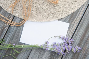 Boş uzay beyaz listesi, lavanta çiçekleri buketi ve ahşap arka planda güneş şapkası, üst manzara, yatay