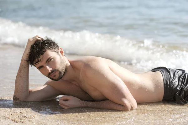 若いですセクシー男ポートレート嘘海の近く トップレスボディ 男は砂の上にリラックス — ストック写真