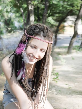 Mutlu gülümseyen kadın portresi Rastalı saç stili çeşitli boncuklar ve tüyler, güneşli açık hava