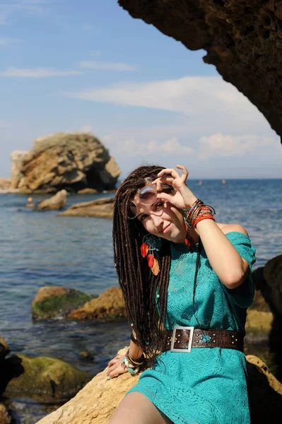 Happy smiling young woman portrait with dreadlocks hairstyle, dressed in turquoise dress, looking at camera