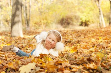 Sonbahar akçaağaç yapraklarında yatan mutlu kız portresi sonbahar parkında gülümsüyor, mutlu çocukluk.