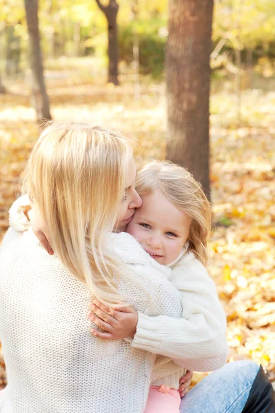 Happy family blonde mother and daughter hugs in autumn forest