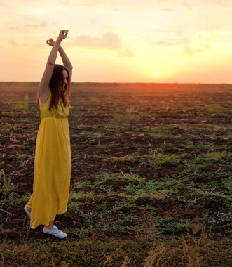 Young woman relaxed dancing with closed eyes in a sunset field, relaxation dances