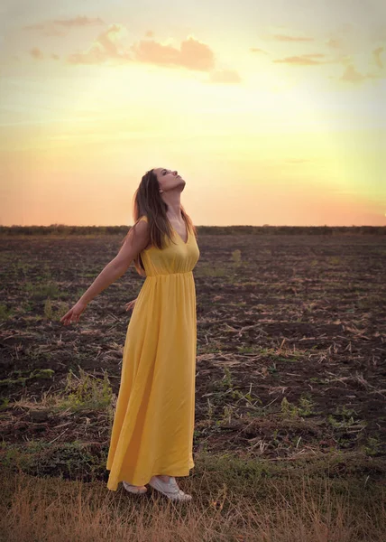 かわいい若い女性は 夕日のフィールドに対して目を閉じて立って 新鮮な空気を呼吸してリラックス — ストック写真