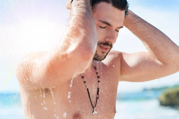 ビーチシャワーでシャワーを浴びてハンサムな魅力的な男性 水滴は彼の裸の胴に落ちています — ストック写真
