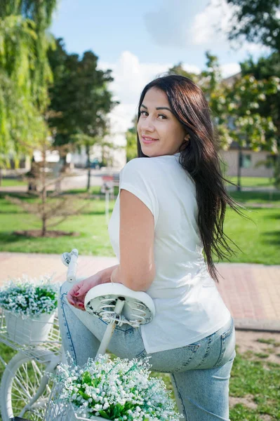 街の周りを白い自転車に乗っている美しい若い女性 — ストック写真