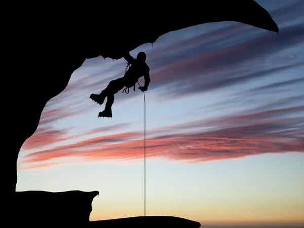 Mountain climber hanging on a rope on the background of sky — Stock Photo, Image