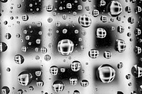 Σταγονίδια νερού ως μικρούς φακούς πάνω από ένα έγχρωμο φόντο. — Φωτογραφία Αρχείου