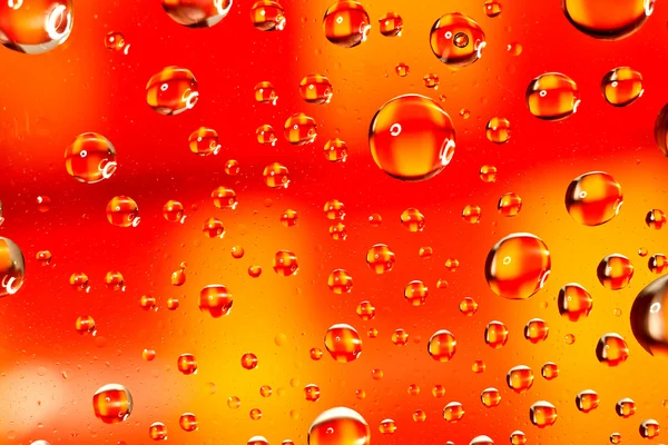 Gotas de agua como lentes pequeñas sobre un fondo de color . — Foto de Stock