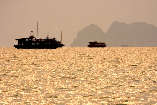 Tradiční vietnamské dřevěné lodě plout v halong bay při západu slunce, vietnam, jihovýchodní Asie. — Stock fotografie