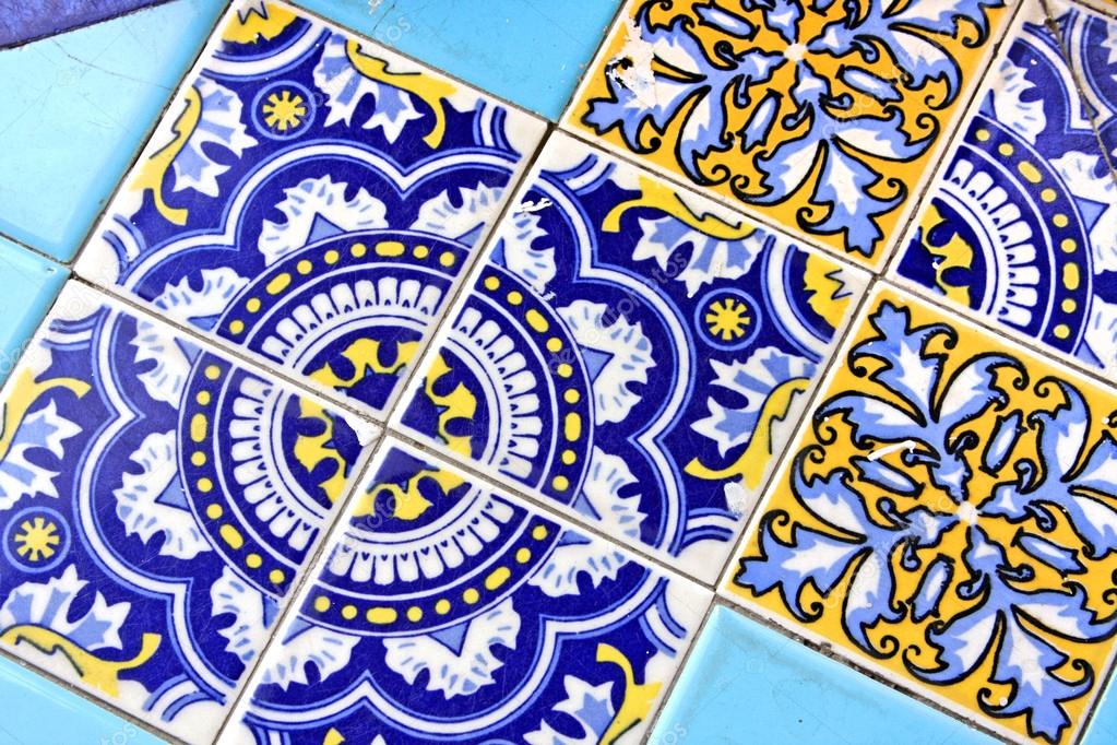 Close up of traditional Spanish ornate ceramic wall tiles. Multi coloured with pale & dark blues & yellow.
