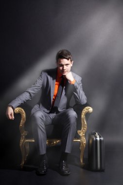 bir adam altın bir sandalyede oturuyor