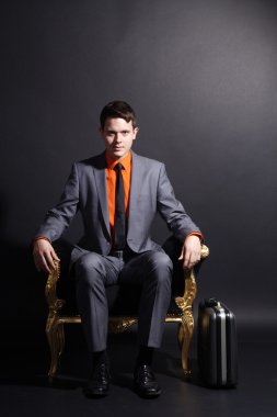 bir adam altın bir sandalyede oturuyor