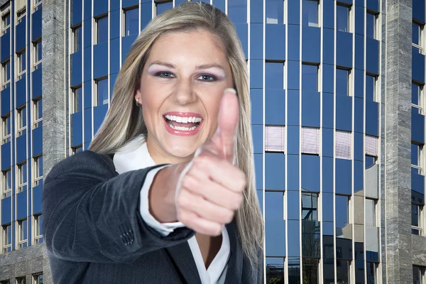 Donna d'affari che mostra OK segno contro un grattacielo — Foto Stock