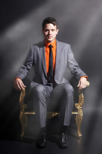 A man is sitting in a golden chair — Stock Photo, Image