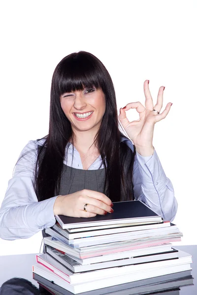 The teacher sits at a table with books and showing ok — Stock Photo, Image