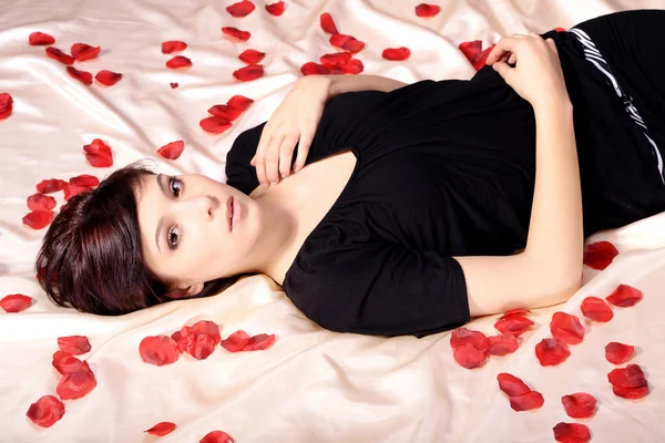 Brunette girl lying on a bed of roses — Stock Photo, Image