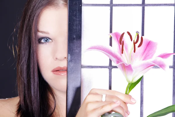 Brünettes Mädchen mit rosa Blume hinter dem Bildschirm — Stockfoto