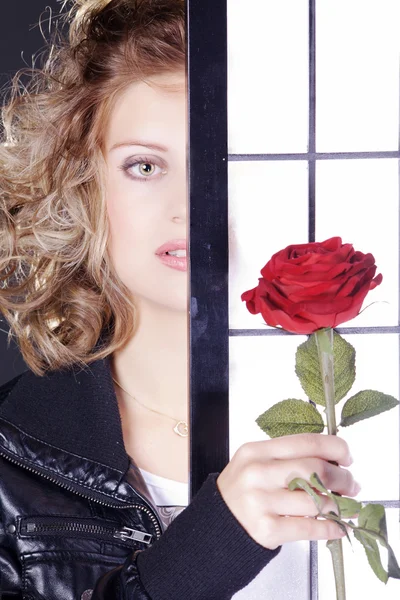 Een meisje met een roos achter het scherm — Stockfoto