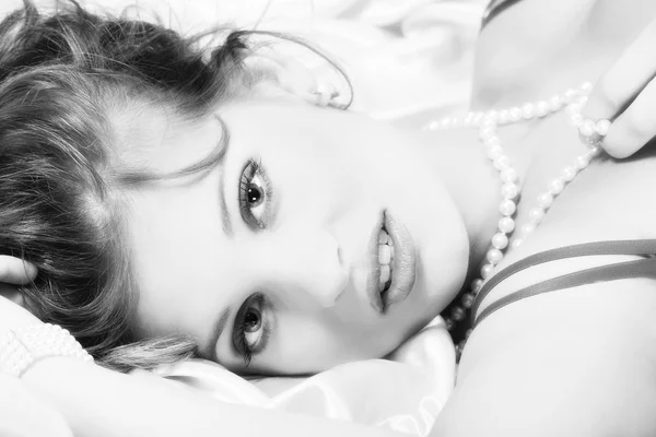 Brunette girl lying on a bed in black and white tone — Stock Photo, Image