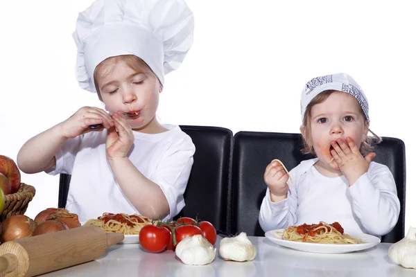 Two little girls in the kitchen eating spaghetti — Stock Photo, Image