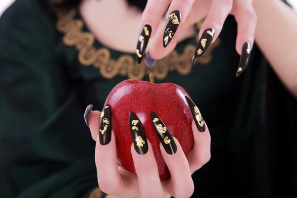 Een meisje met lange nagels houden een appel — Stockfoto