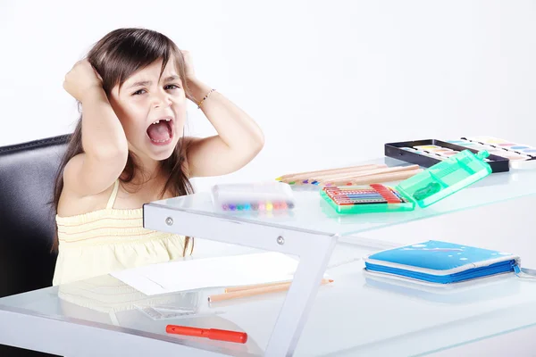 La petite fille fait ses devoirs assis à table — Photo