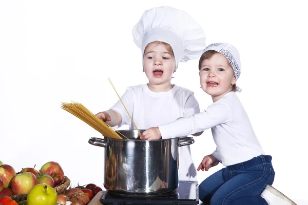 Two little girls in the kitchen eating spaghetti — Stock Photo, Image