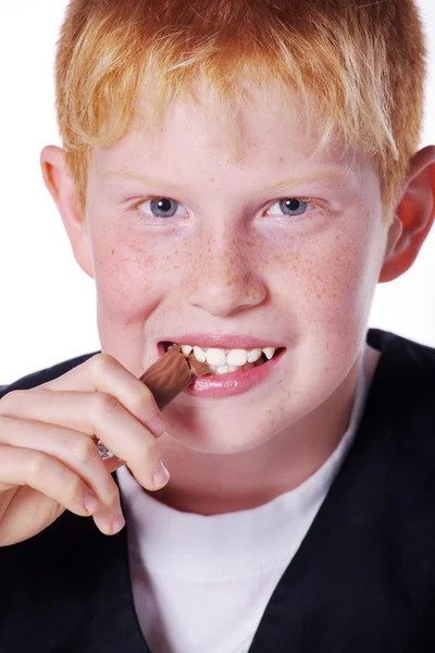 Roodharige jongen eten chocolade bar — Stockfoto