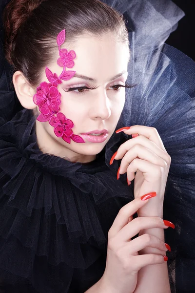 Brünettes Mädchen mit rosa Blumen im Gesicht — Stockfoto