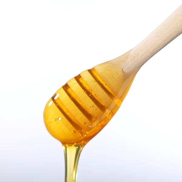 Honey dripping from a wooden dipper isolated on a white background — Stock Photo, Image