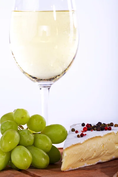 A glass of champagne and cake and grapes — Stock Photo, Image