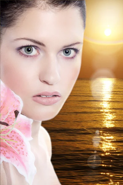 Naga brunetka dziewczynka z kwiatem na tle zachodu słońca morze — Zdjęcie stockowe