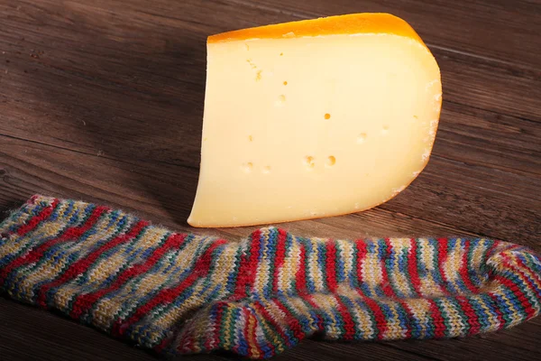Cheese with a sock on a wooden table — Stock Photo, Image