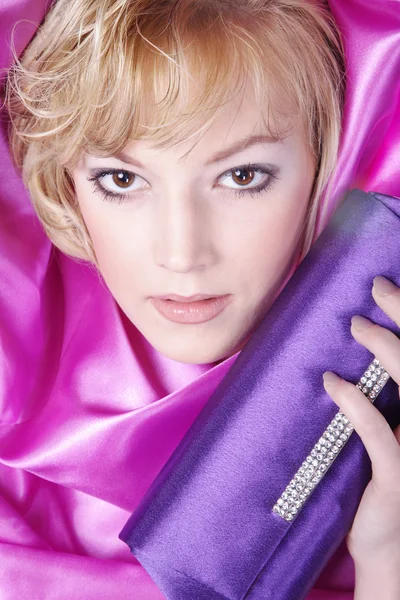 Blonde girl with handbag in a pink curtain — Stock Photo, Image