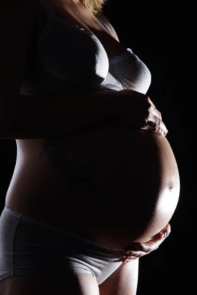 Fille enceinte sur un fond sombre — Photo