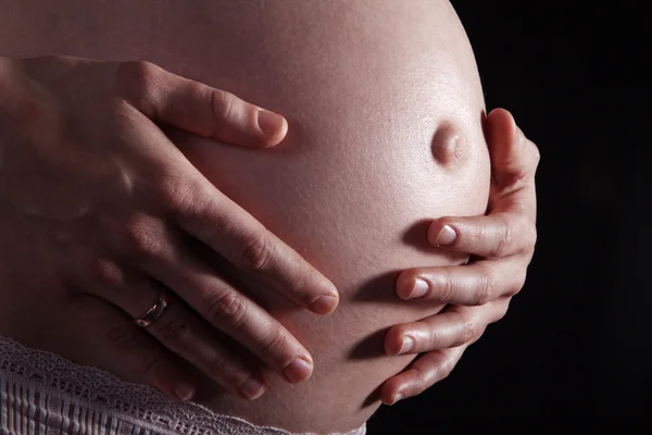 Zwangere meisje op een donkere achtergrond — Stockfoto