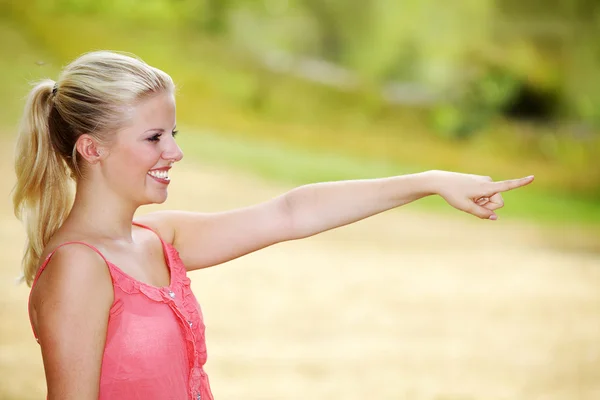 Blond tjej visar ett tecken — Stockfoto