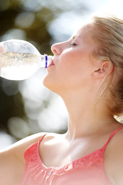 Blonde girl drinks water in a bottle — Stock Photo, Image