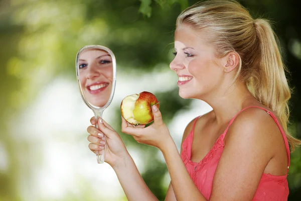 Blonde girl with apple and mirror — Stock Photo, Image