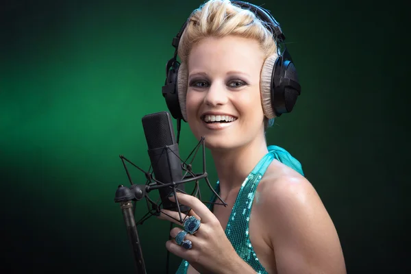 Blonde girl singing into a microphone — Stock Photo, Image