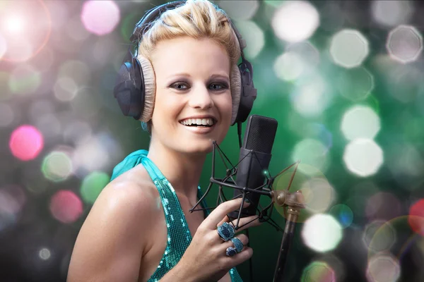 Menina loira cantando em um microfone — Fotografia de Stock